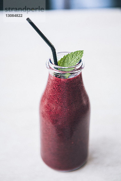 Nahaufnahme eines Smoothie in der Flasche mit Trinkhalm auf dem Tisch