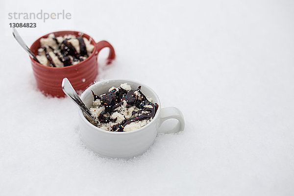 Nahaufnahme eines Desserts mit Löffeln in Tassen auf Schnee