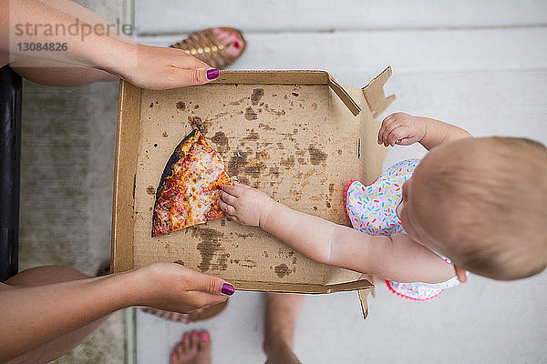 Draufsicht der Mutter  die der Tochter Pizza gibt