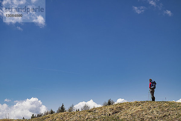 Tiefwinkelaufnahme einer Wanderin  die auf einem Berg vor blauem Himmel steht
