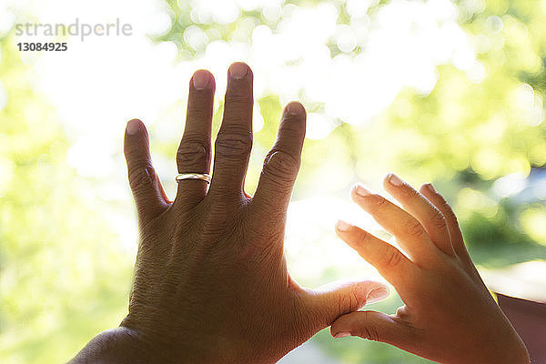 Vater und Kind berühren Finger gegen Sonnenlicht