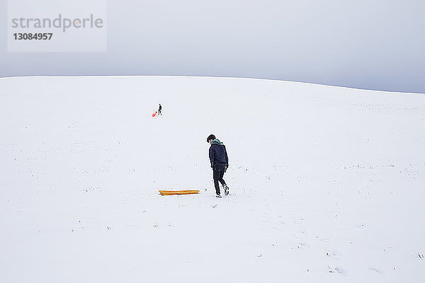 Männer mit Schlitten auf schneebedeckten Bergen gegen den Himmel