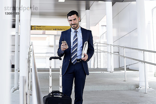 Porträt eines selbstbewussten Geschäftsmannes mit Smartphone in der U-Bahn-Station
