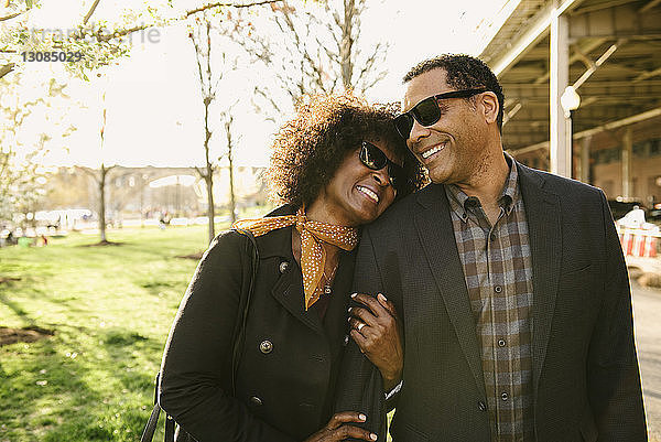 Glückliches Paar trägt Sonnenbrille  während es im Park steht