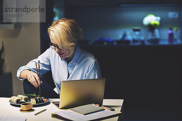 Geschäftsfrau  die am Schreibtisch sitzend im Home-Office Essen sucht