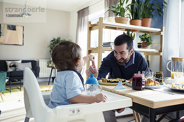 Glücklicher Vater spielt mit seinem Sohn beim Frühstück zu Hause