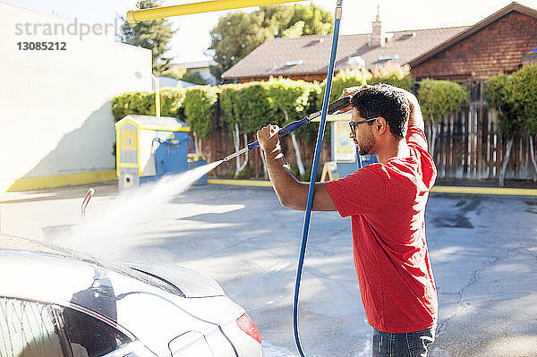 Mann reinigt Auto an Einfahrt