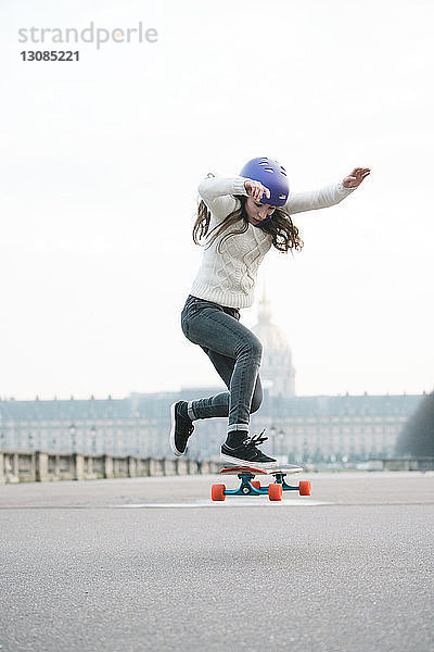 Frau springt in voller Länge beim Skateboardfahren gegen Musee de larmee