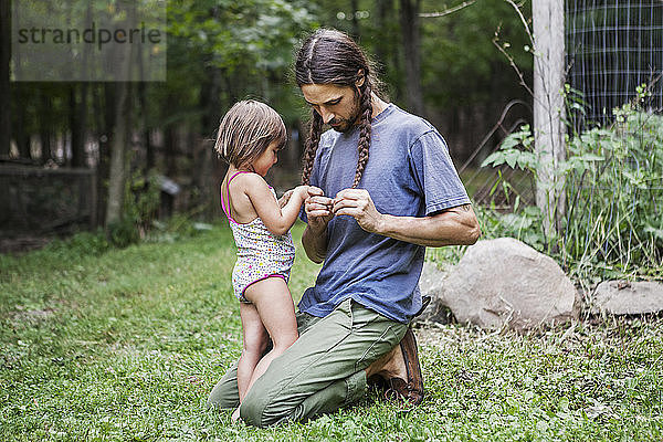 Vater und Tochter flechten Haare im Hinterhof