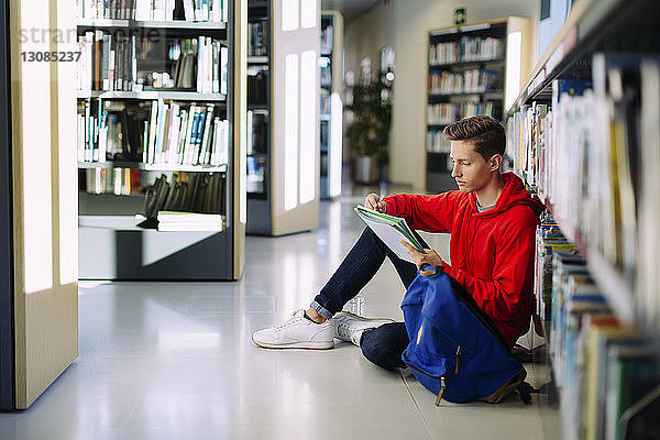 Mann lernt  während er in der Bibliothek auf dem Boden sitzt