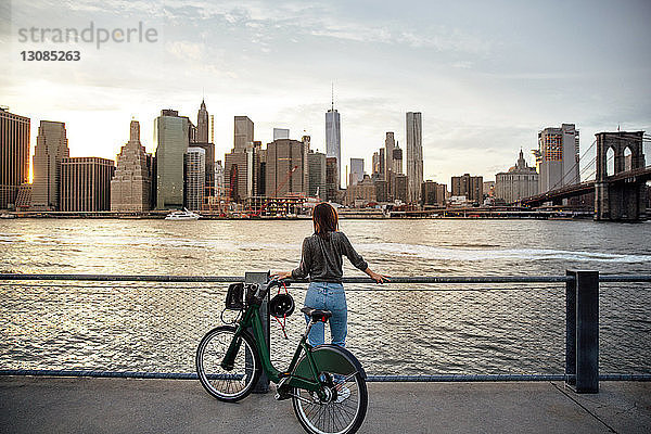 Rückansicht einer Frau mit Fahrrad  die die Stadtansicht betrachtet  während sie auf dem Beobachtungspunkt steht