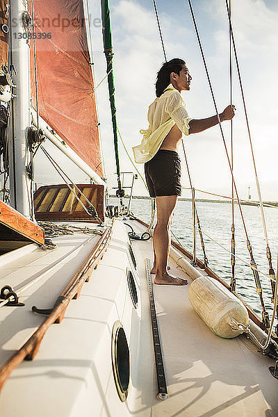 Seitenansicht eines Mannes  der an Deck eines Segelbootes steht