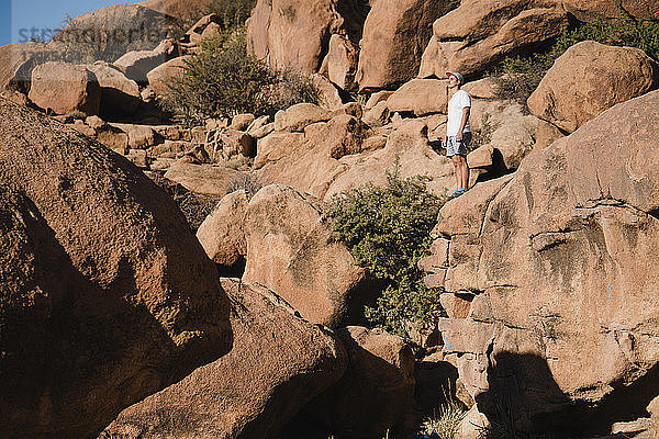 Mann in voller Länge  der bei Sonnenschein auf Felsen in der Wüste steht