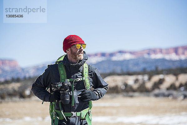 Wanderer mit Rucksack und Kamera steht im Winter in der Wüste