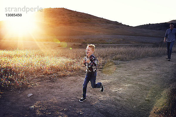 Junge läuft an einem sonnigen Tag auf dem Feld