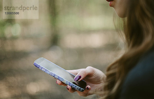 Nahaufnahme einer jungen Frau mit einem Smartphone im Park