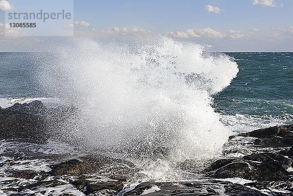Wellen brechen auf Felsen am Strand