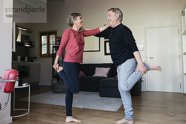 Seitenansicht eines fröhlichen Seniorenpaares  das zu Hause Sport treibt