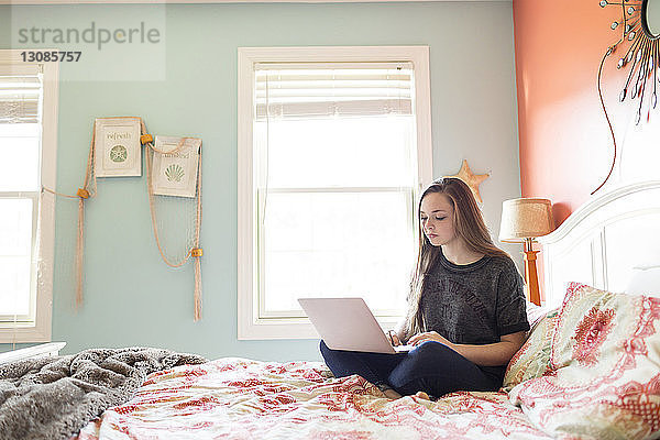Frau benutzt Laptop-Computer zu Hause am Bett