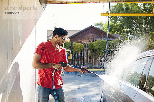 Mann wäscht Auto in Garage an sonnigem Tag