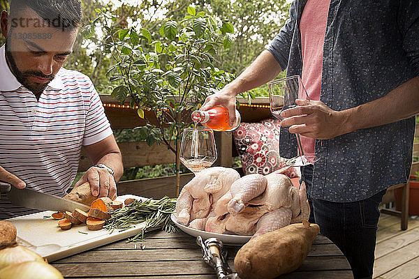 Homosexuelle Männer kochen Essen bei Tisch im Urlaubsort