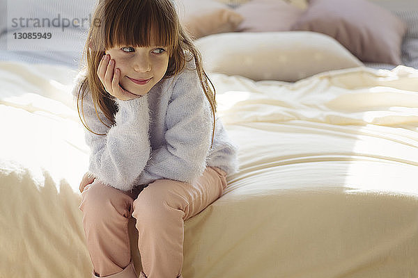 Nachdenkliches Mädchen sitzt auf dem Bett