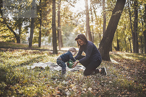 Mutter und Sohn spielen im Herbst im Park mit dem Ball