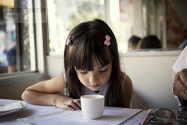 Mädchen schaut in Tasse auf den Tisch  während sie im Restaurant sitzt