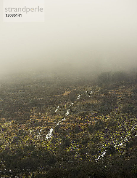 Szenische Ansicht des Wasserfalls über dem Berg bei nebligem Wetter
