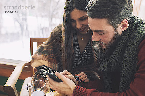 Hochwinkelansicht eines Paares bei der Benutzung eines Mobiltelefons im Cafe