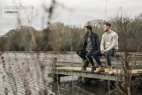 Freunde schauen weg  während sie auf der Mole über dem See im Eppinger Wald sitzen