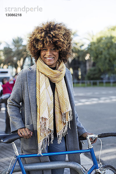 Porträt einer glücklichen Frau mit Fahrrad im Park stehend