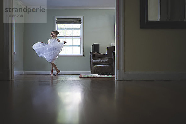 Mädchen in voller Länge in weißem Kleid tanzt zu Hause im Zimmer