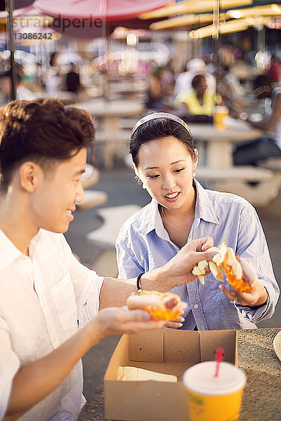 Paar  das Hot Dogs isst  während es im Straßencafé sitzt