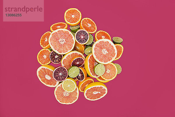 Draufsicht auf verschiedene Zitrusfrüchte auf rosa Hintergrund