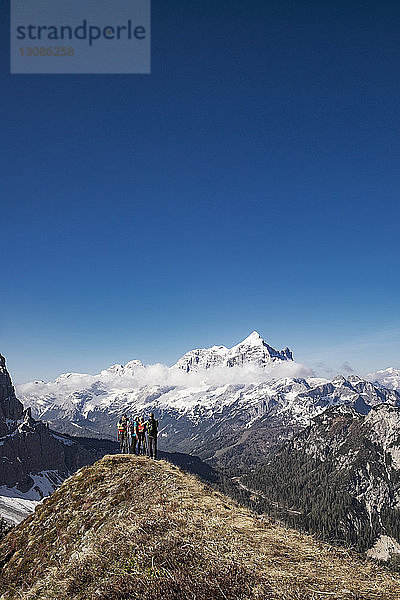 Wanderer stehen auf Berg vor klarem blauen Himmel