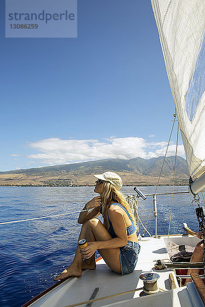 Mittlere erwachsene Frau auf dem Yachtdeck sitzend