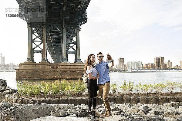 Selbstmord eines Pärchens  das auf Felsen unter der Manhattan-Brücke vor klarem Himmel steht