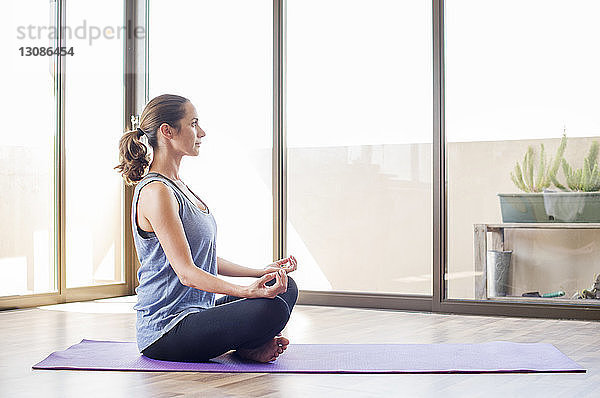 Seitenansicht einer Frau  die zu Hause Yoga praktiziert