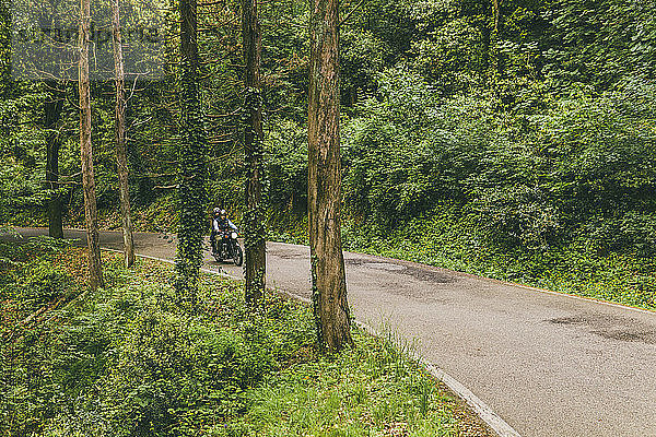 Paar fährt Motorrad auf Straße im Wald