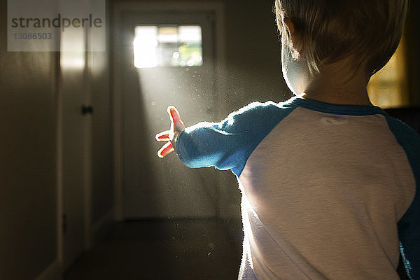 Sonnenlicht fällt zu Hause durch die Tür auf den Jungen