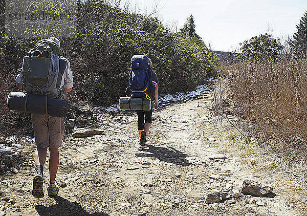 Rückansicht von Wanderern mit Rucksäcken auf dem Feldweg im Pisgah National Forest