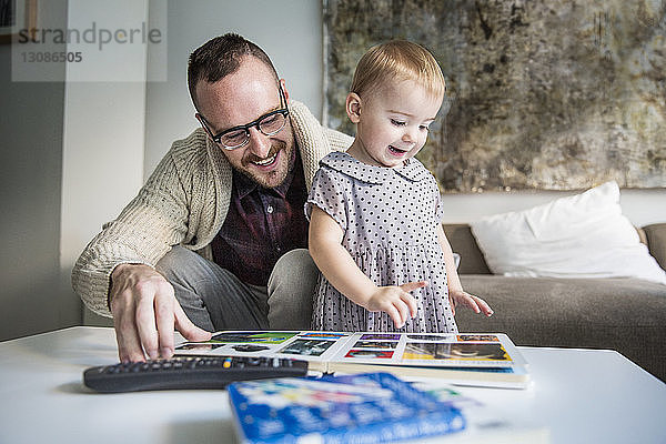 Glücklicher Vater liest seiner Tochter zu Hause ein Bilderbuch vor