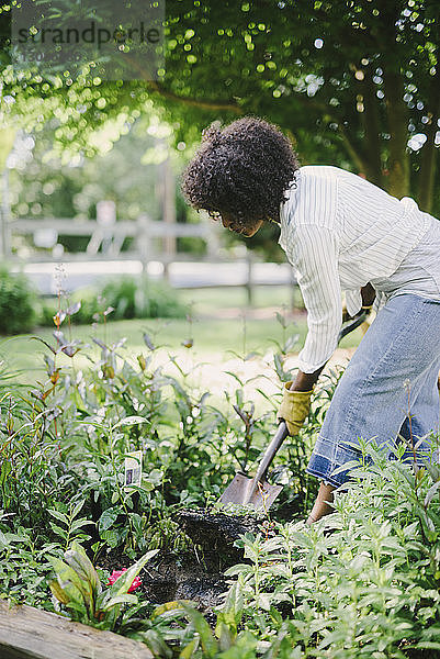 Frau gräbt Erde mit Schaufel im Garten
