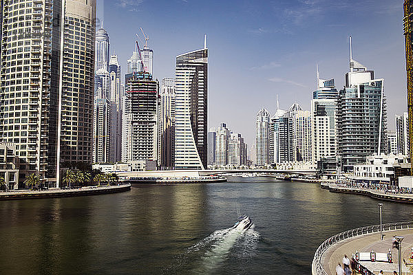 Boot bewegt sich auf dem Dubai Creek inmitten moderner Gebäude gegen den Himmel