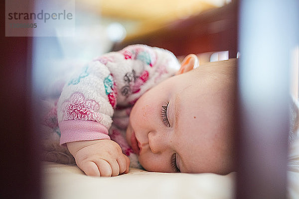 Nahaufnahme eines im Gitterbett schlafenden Mädchens