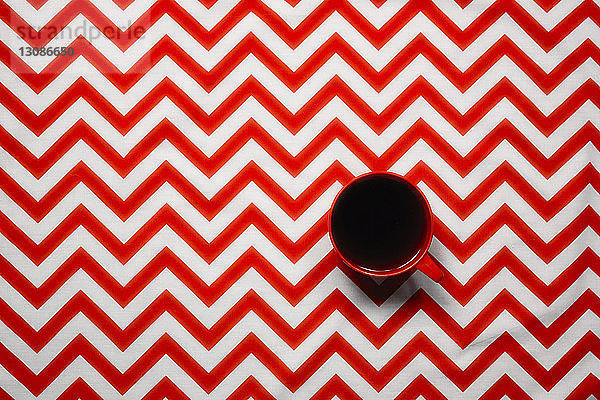 Draufsicht auf schwarzen Kaffee  der in einer Tasse auf einem Tisch mit Chevron-Muster serviert wird