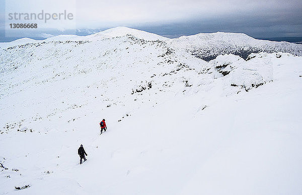 Hochwinkelansicht von Wanderern auf schneebedecktem Berg gegen den Himmel