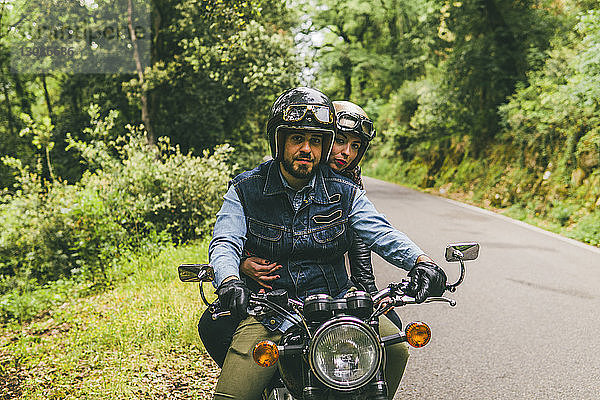 Porträt eines Motorrad fahrenden Ehepaares auf einer Straße im Wald