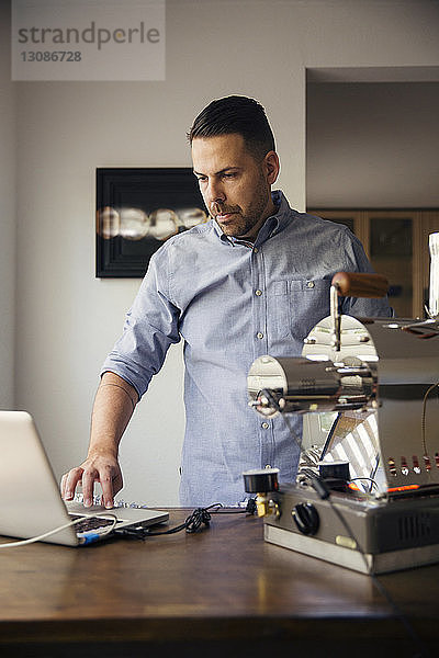 Mann benutzt Laptop und Kaffeeröster im Café